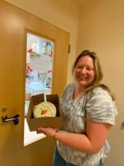 A lab member poses with a cake outside the lab