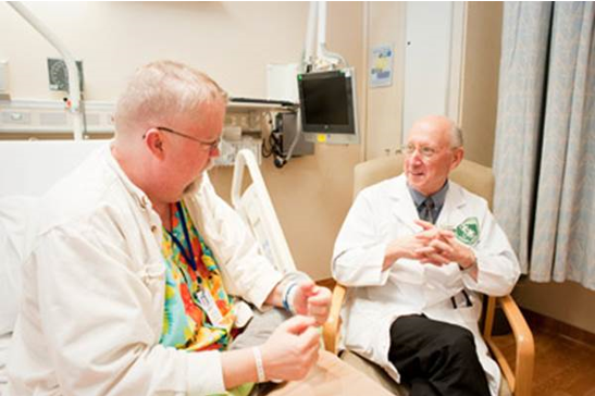Dr. Steven A. Rosenberg speaking with a patient at the NIH Clinical Center.