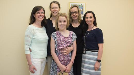 A young patient with NF1 who was treated at NCI gathers with her mother and members of NCI’s Pediatric Oncology Branch.