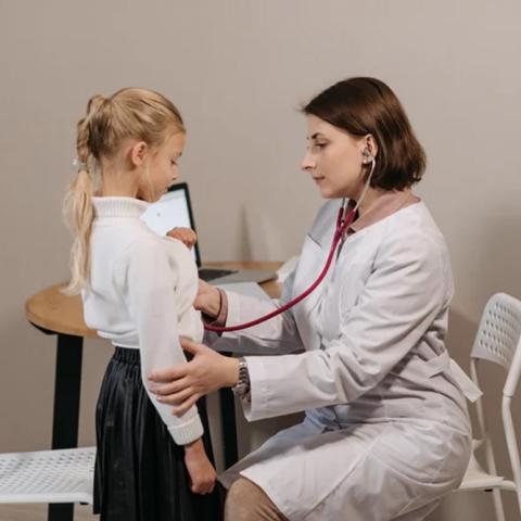 image of female physician using a stethoscope on a young female patient