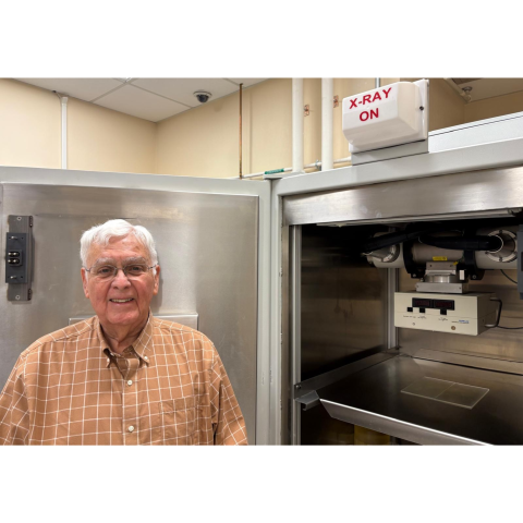 Jim Mitchell in front of a machine and a sign that says X-ray on