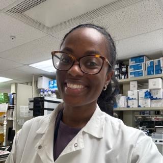 Treshaun, dressed in a lab coat, smiles at the camera