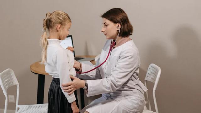 image of female physician using a stethoscope on a young female patient