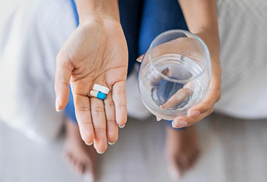 Hand holding pills and cup of water
