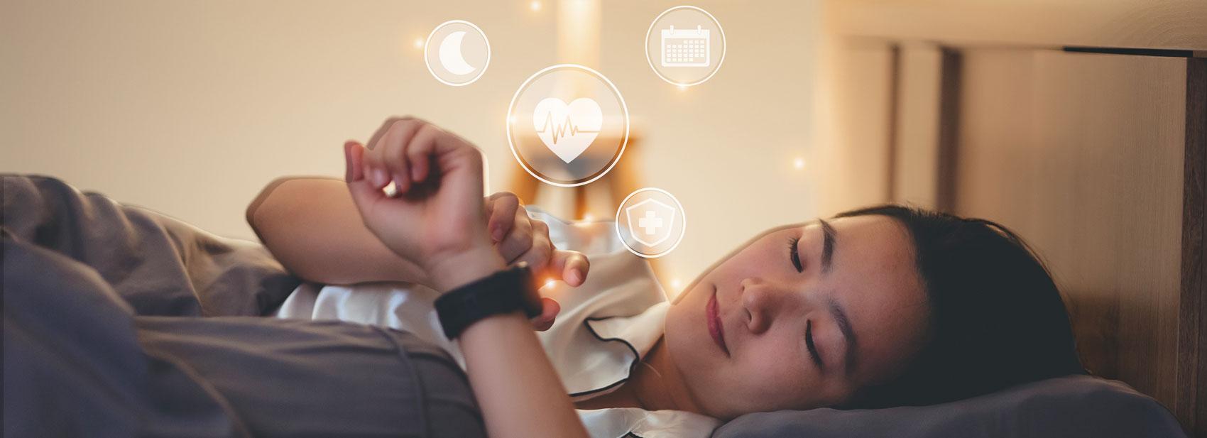 Woman lying in bed looking at her watch, which displays moon, heartbeat, calendar, and medical icons