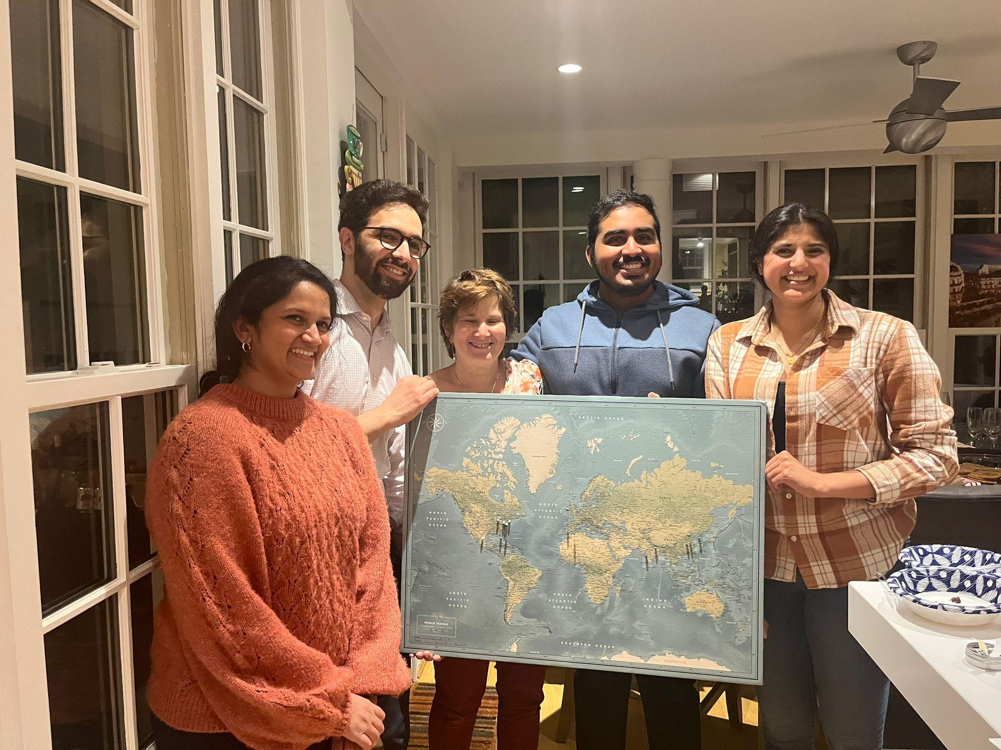 The group poses with a large map showing where lab members will move on to in their next research positions.