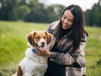 A woman smiling with her hands around her dog.